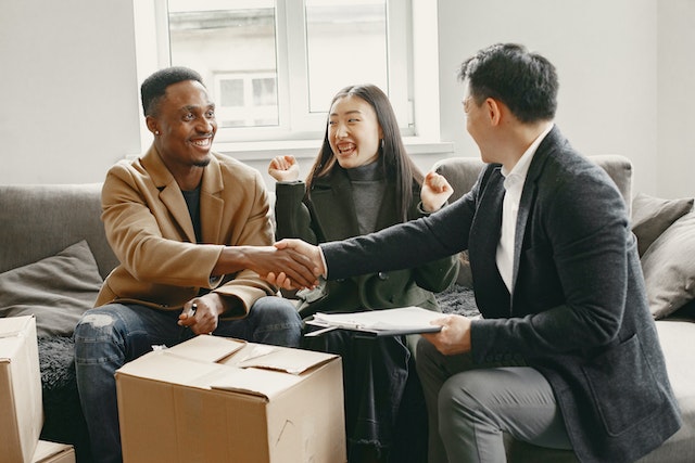 three people smiling as two new tenants sign a lease agreement